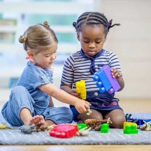 Two children playing with large colored connecting blocks.